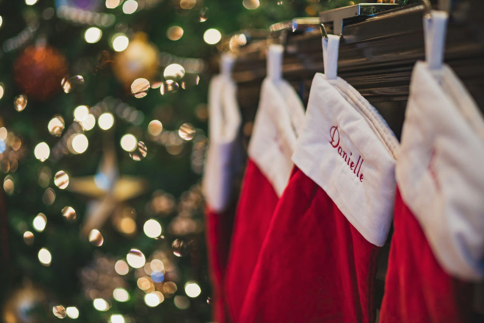 Four red and white Christmas stockings hanging in a row, ready for stocking stuffers for kids