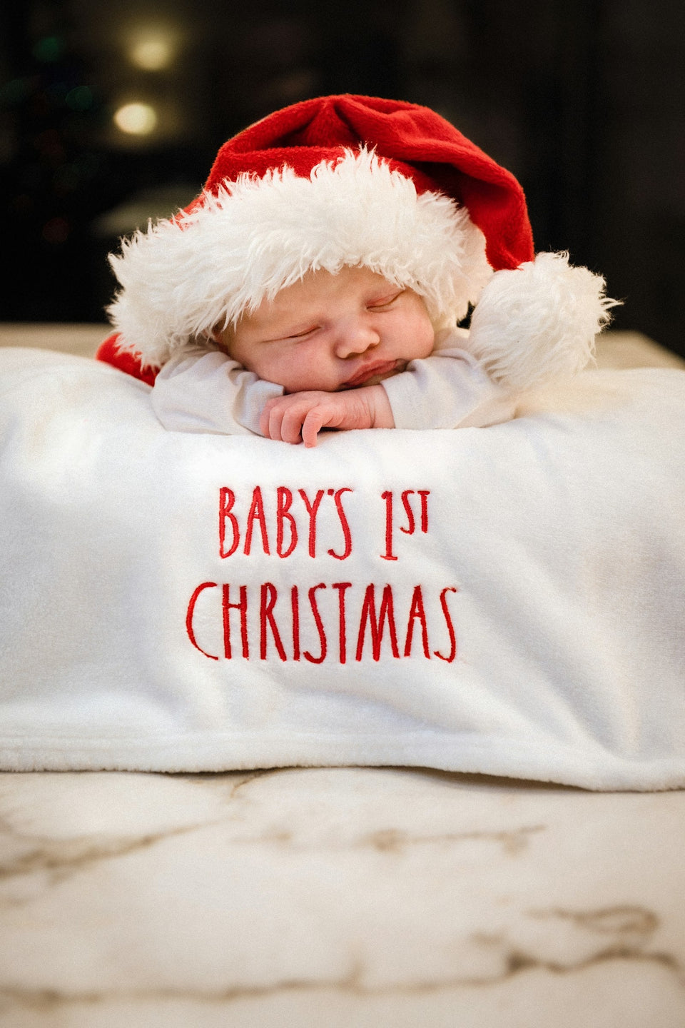 Newborn baby in a Santa hat on a baby's 1st Christmas blanket