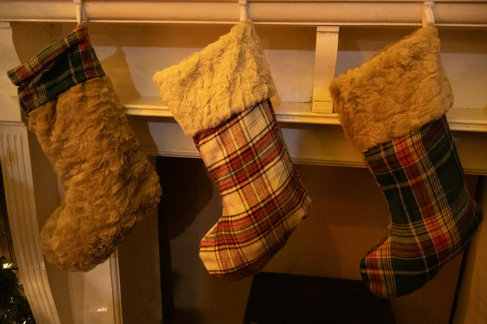 Three Christmas stockings hanging on a wooden mantel