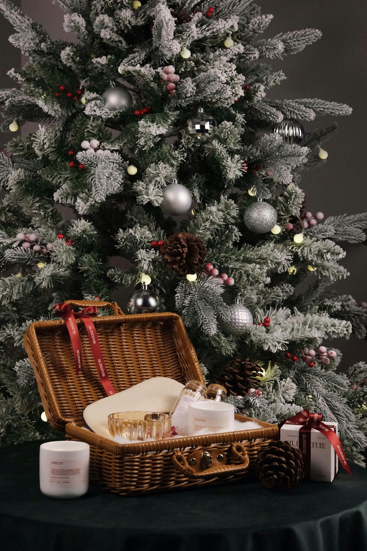 Christmas gift basket filled with treats sitting next to a decorated Christmas tree