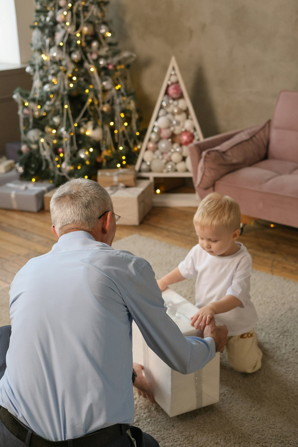 Grandpa opening a Christmas gift with his grandchild